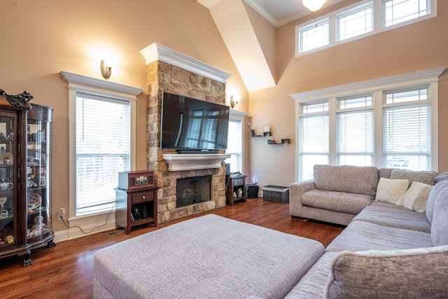 living room with dark wood-type flooring, a towering ceiling, a fireplace, and crown molding