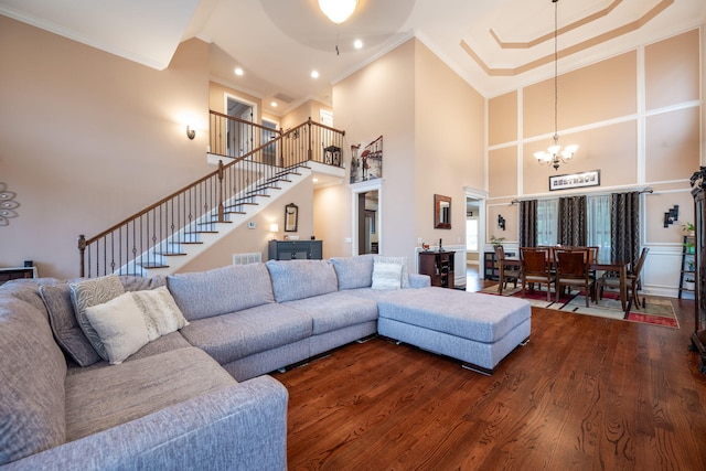 living room featuring a high ceiling, crown molding, hardwood / wood-style floors, and a notable chandelier