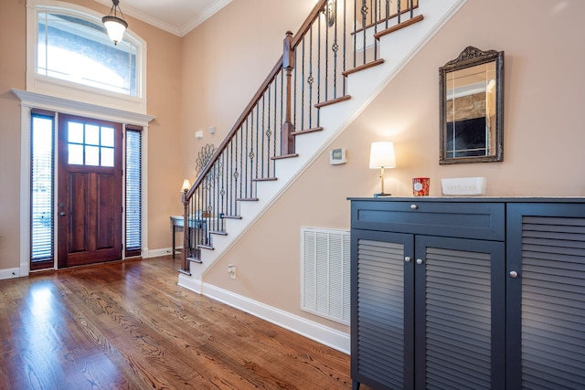 foyer with crown molding, dark hardwood / wood-style flooring, and a high ceiling