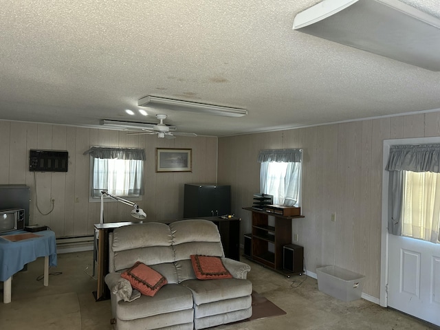 living room featuring a baseboard heating unit, a textured ceiling, a healthy amount of sunlight, and ceiling fan