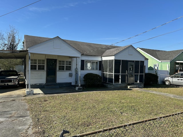 view of front of house with a carport, a sunroom, and a front yard