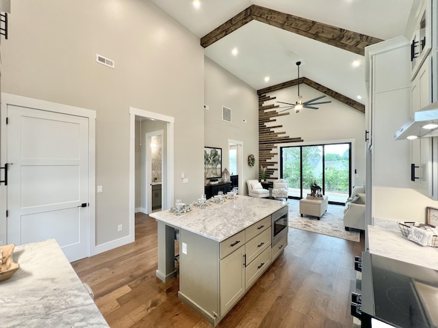 kitchen featuring high vaulted ceiling, open floor plan, wood finished floors, ceiling fan, and a kitchen island