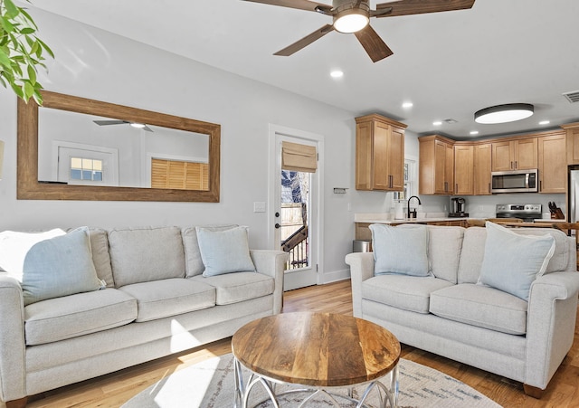 living room with ceiling fan, sink, and light hardwood / wood-style floors