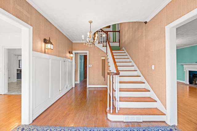 stairs featuring crown molding, a chandelier, and hardwood / wood-style floors