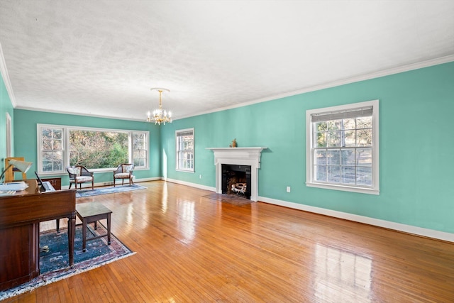 living room featuring an inviting chandelier, ornamental molding, light hardwood / wood-style floors, and a textured ceiling