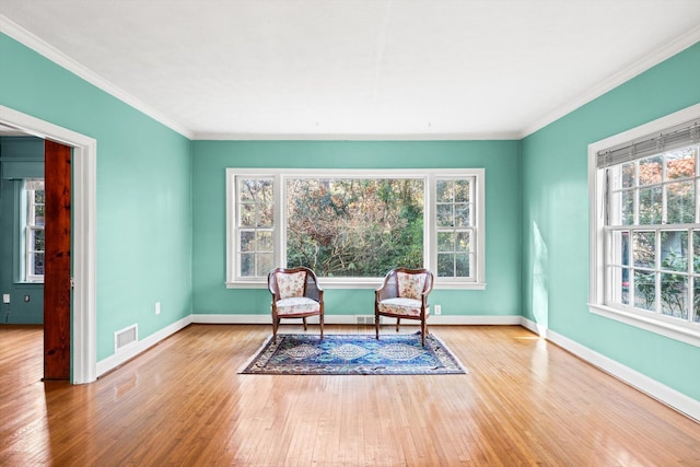 living area featuring ornamental molding, plenty of natural light, and light hardwood / wood-style flooring