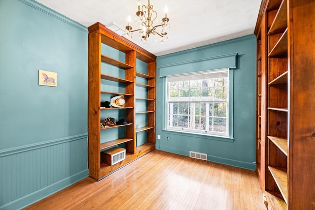 interior space with a notable chandelier, crown molding, and light hardwood / wood-style flooring