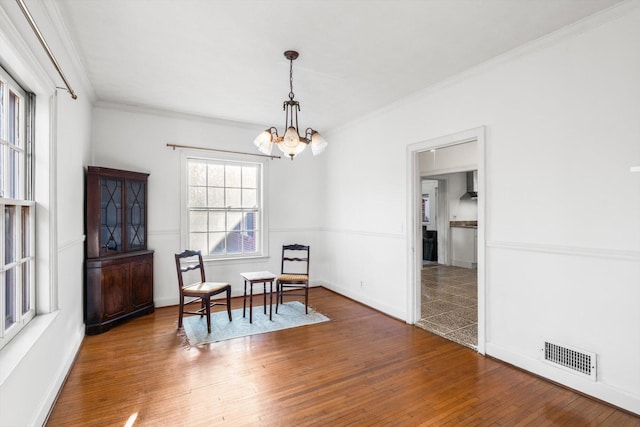 dining area with dark wood-type flooring, ornamental molding, and a chandelier