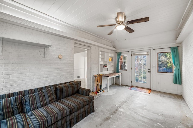 living room featuring concrete flooring, brick wall, lofted ceiling, and ceiling fan