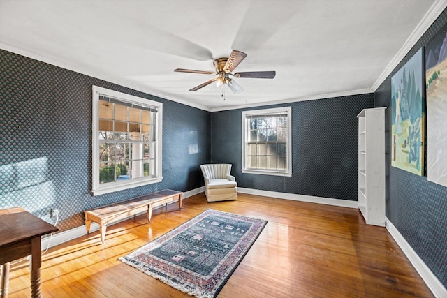 living area featuring hardwood / wood-style flooring, a wealth of natural light, ornamental molding, and ceiling fan