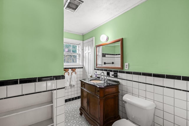 bathroom featuring vanity, tile walls, a textured ceiling, and toilet