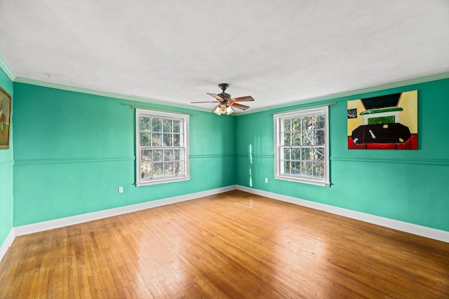 empty room with hardwood / wood-style floors, ornamental molding, a wealth of natural light, and ceiling fan