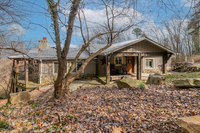 single story home featuring a patio area, a chimney, metal roof, and board and batten siding