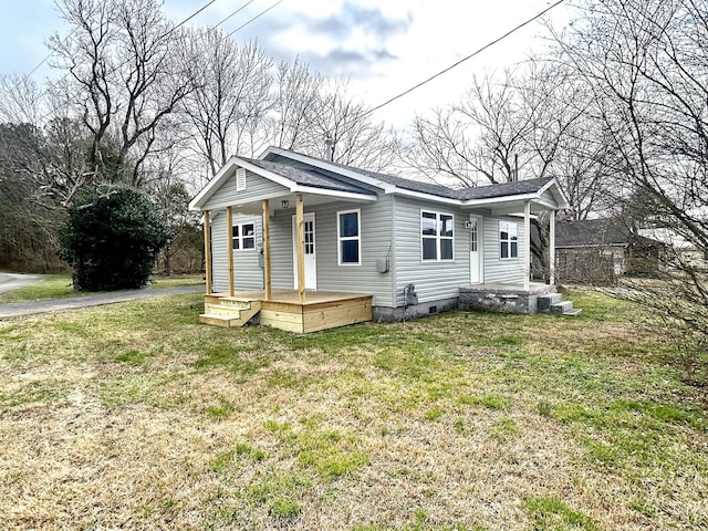 bungalow-style house featuring a porch, roof with shingles, and a front yard