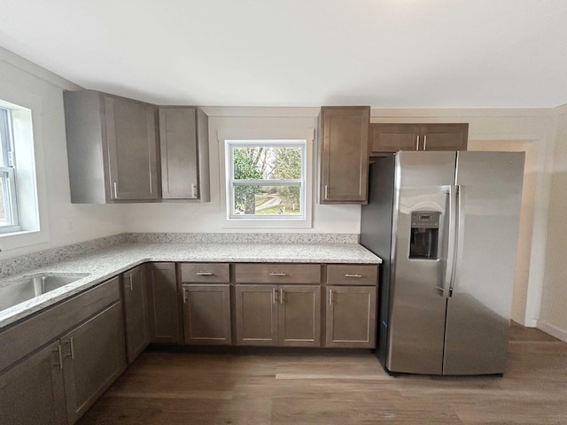 kitchen featuring sink, stainless steel fridge, hardwood / wood-style floors, and light stone countertops