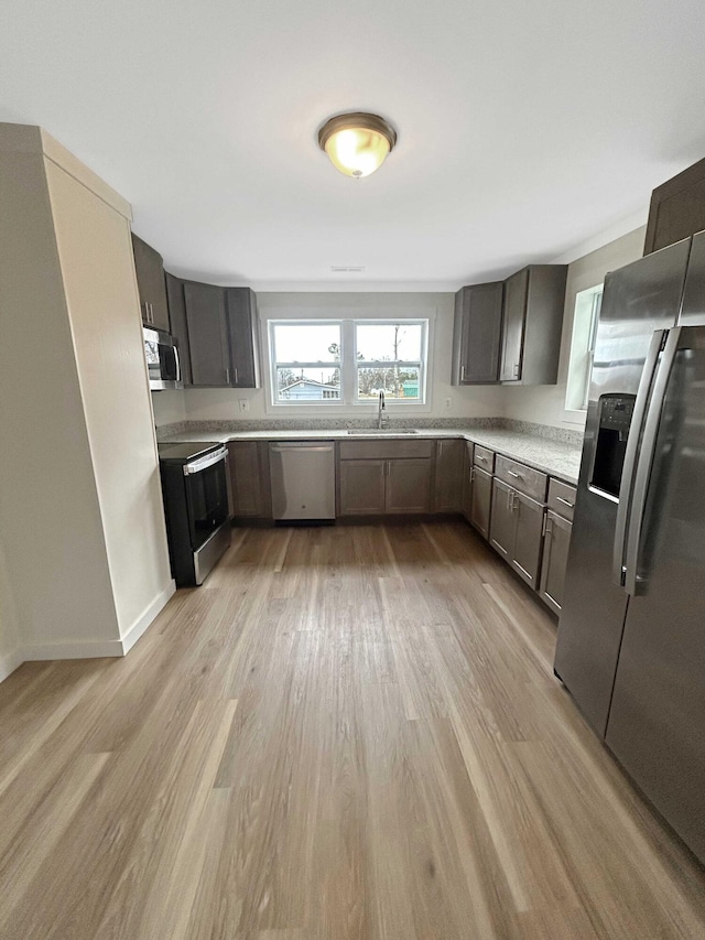 kitchen featuring dark brown cabinetry, sink, stainless steel appliances, and light hardwood / wood-style floors