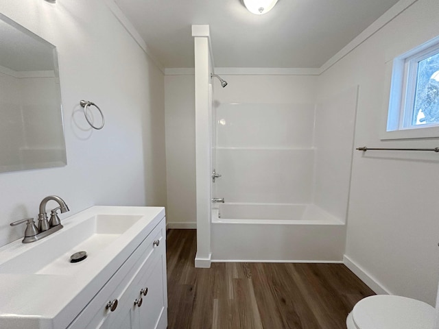 full bathroom featuring toilet, washtub / shower combination, vanity, wood finished floors, and baseboards