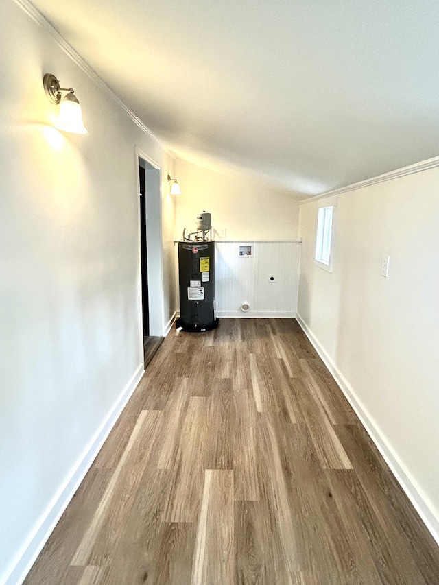 interior space with dark wood-type flooring, electric water heater, ornamental molding, and baseboards