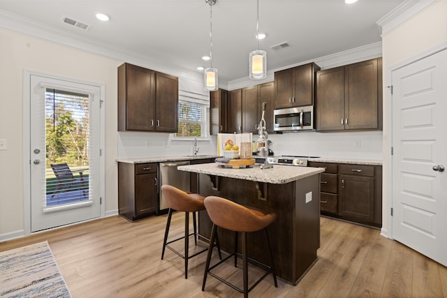 kitchen with stainless steel appliances, a kitchen bar, a center island, and dark brown cabinetry