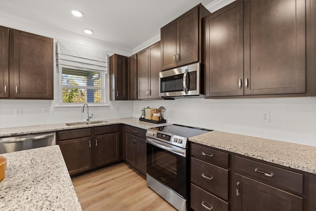 kitchen with tasteful backsplash, sink, light stone counters, stainless steel appliances, and light wood-type flooring