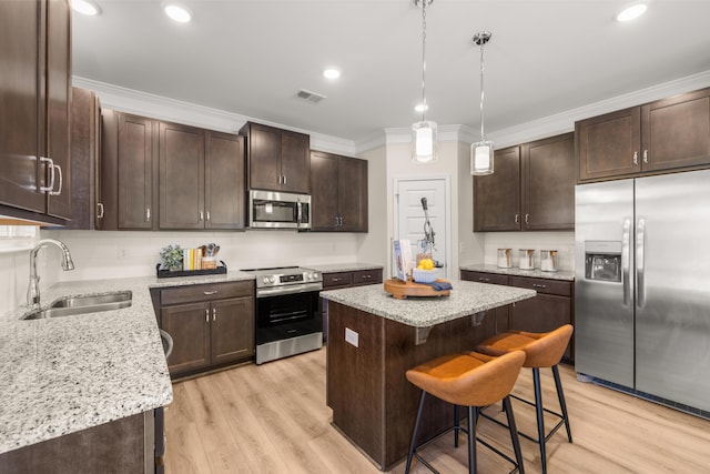 kitchen featuring sink, crown molding, a center island, appliances with stainless steel finishes, and a kitchen breakfast bar