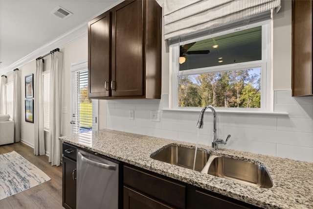 kitchen featuring dark brown cabinetry, sink, ornamental molding, dishwasher, and light stone countertops