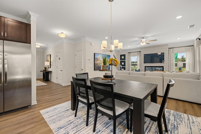 dining space featuring crown molding, ceiling fan with notable chandelier, and light hardwood / wood-style floors