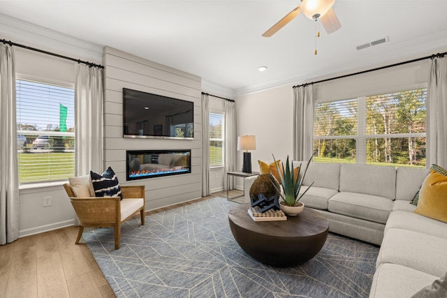 living room featuring light hardwood / wood-style flooring, ornamental molding, and ceiling fan