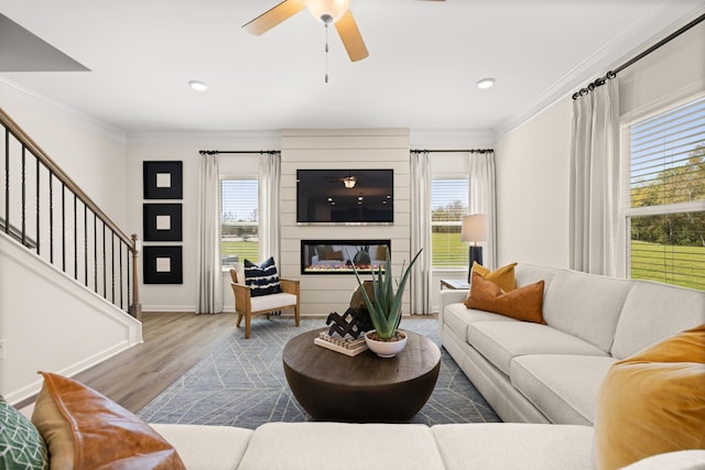 living room featuring crown molding, plenty of natural light, a fireplace, and light wood-type flooring