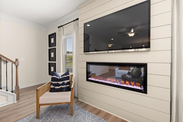 living area with hardwood / wood-style floors, crown molding, and ceiling fan