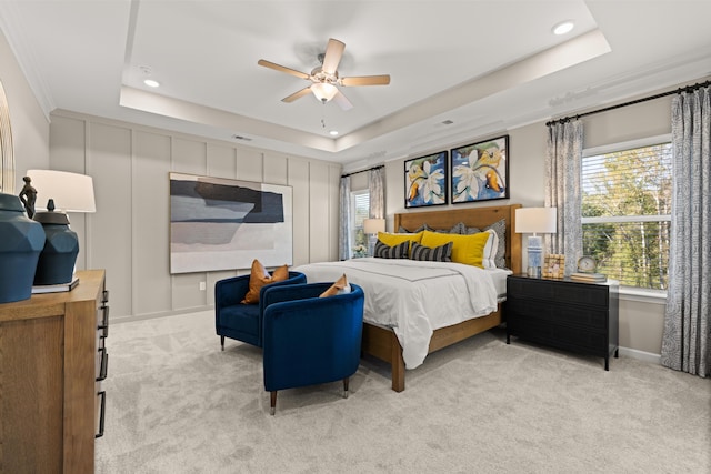 bedroom with a raised ceiling, light carpet, and ceiling fan