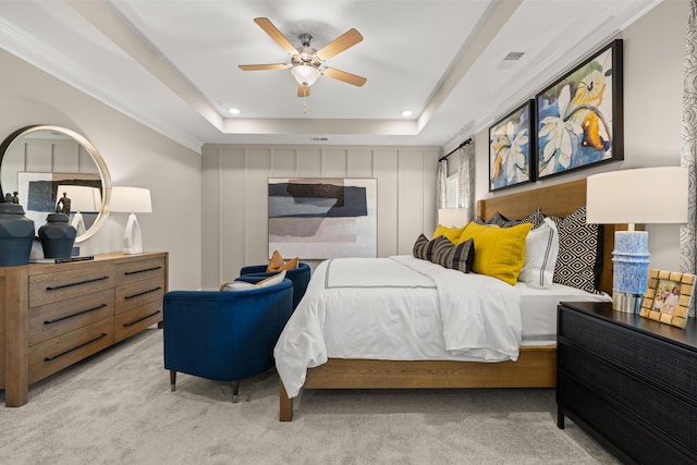 carpeted bedroom with a raised ceiling and ceiling fan