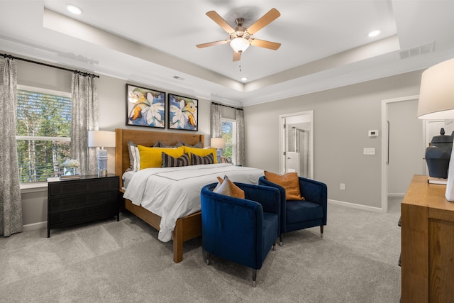 carpeted bedroom featuring connected bathroom, ceiling fan, and a tray ceiling