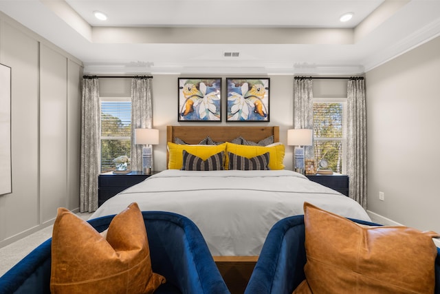 carpeted bedroom with ornamental molding and a tray ceiling