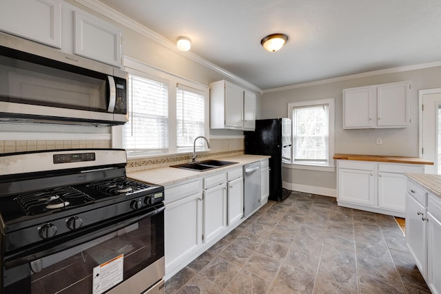 kitchen with ornamental molding, sink, stainless steel appliances, and white cabinetry