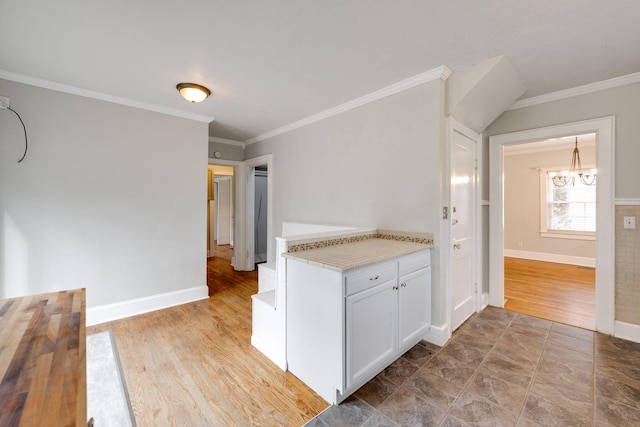 kitchen featuring light hardwood / wood-style flooring, an inviting chandelier, decorative light fixtures, crown molding, and white cabinets