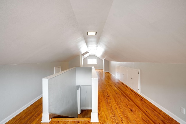 additional living space with light hardwood / wood-style floors and lofted ceiling