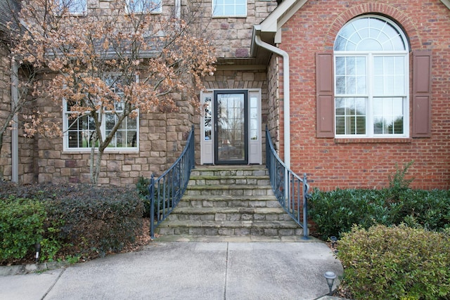 view of exterior entry featuring stone siding and brick siding