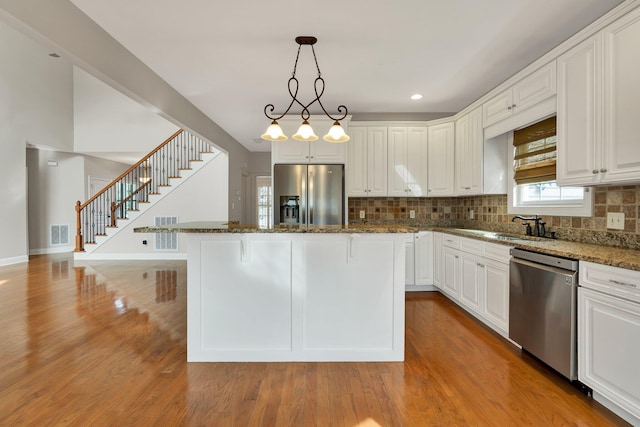 kitchen with visible vents, dark stone countertops, a center island, stainless steel appliances, and light wood finished floors