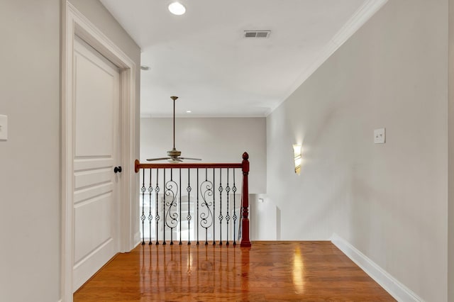 hall featuring visible vents, an upstairs landing, wood finished floors, and ornamental molding