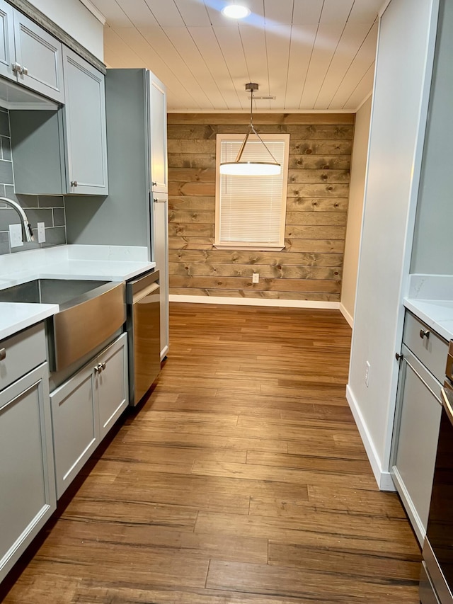 kitchen with light countertops, a sink, stainless steel dishwasher, and wood finished floors