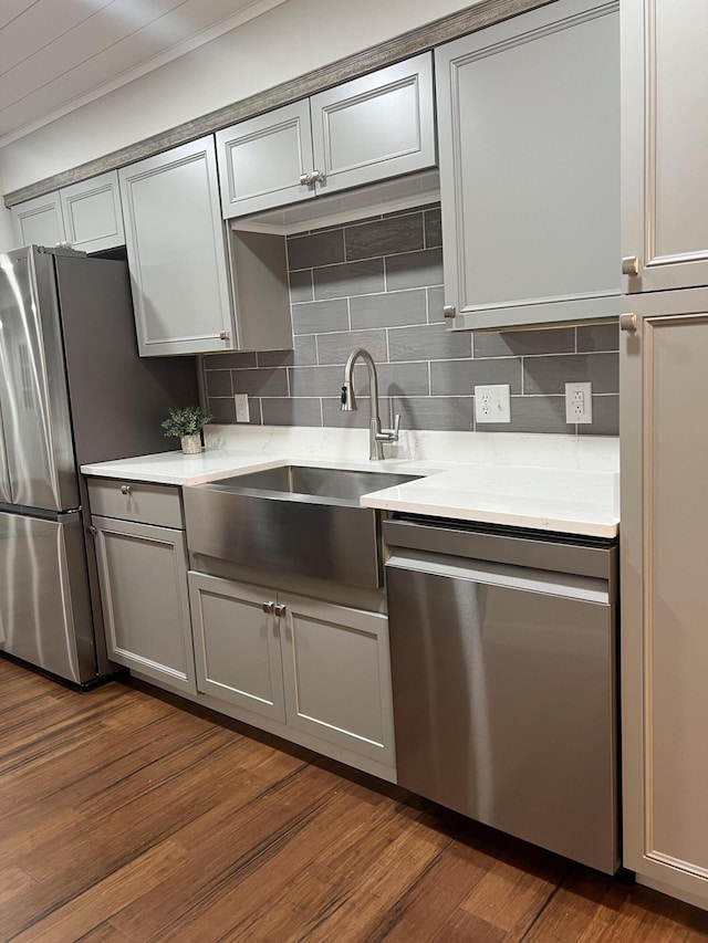 kitchen with light countertops, decorative backsplash, gray cabinetry, appliances with stainless steel finishes, and a sink