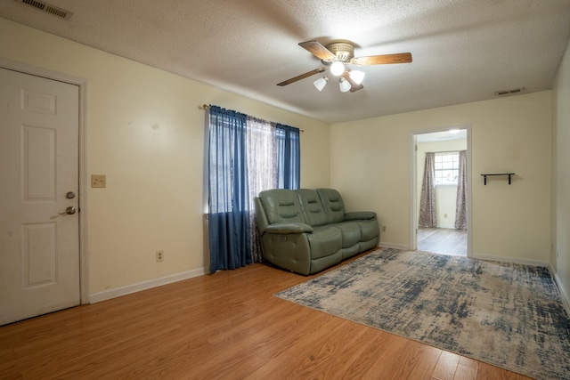 living room with ceiling fan, hardwood / wood-style floors, and a textured ceiling