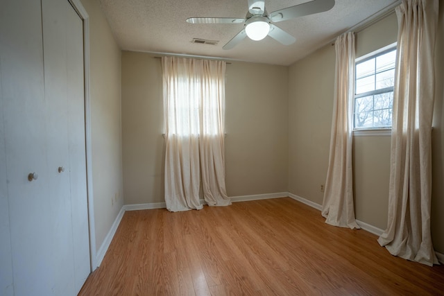 empty room featuring ceiling fan, a textured ceiling, and light wood-type flooring