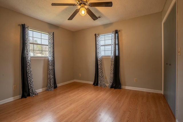 spare room featuring plenty of natural light, light hardwood / wood-style floors, and a textured ceiling