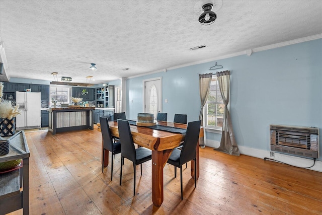 dining space with hardwood / wood-style floors, crown molding, heating unit, and a textured ceiling