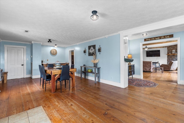 dining space featuring hardwood / wood-style flooring, ornamental molding, and a textured ceiling