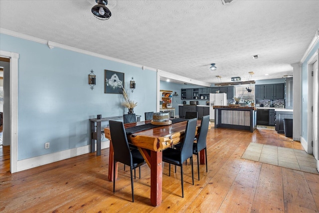 dining area featuring crown molding, a textured ceiling, and light hardwood / wood-style flooring