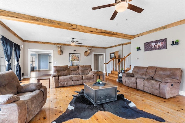 living room with ceiling fan, beam ceiling, wood-type flooring, and a textured ceiling