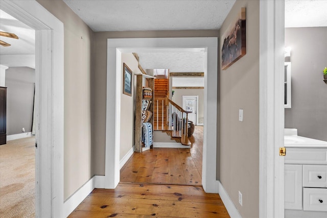 corridor with hardwood / wood-style floors and a textured ceiling